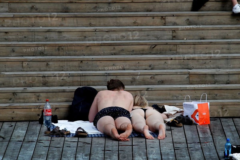 Relaxing bathers on wooden steps in the Bjøvika sun in Oslo, Oslo, Bjøvika, Norway