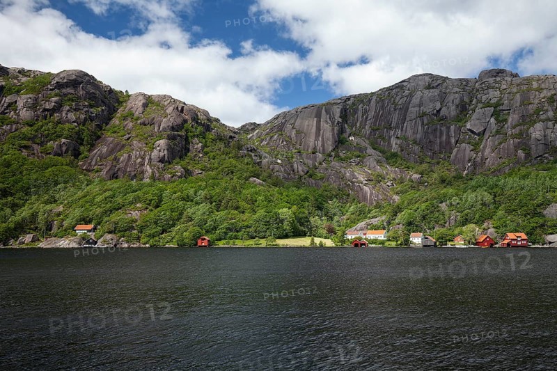 Red cabins by a lake with granite mountains in the background. Summer, Highland (Terra alta), Agder, Norway
