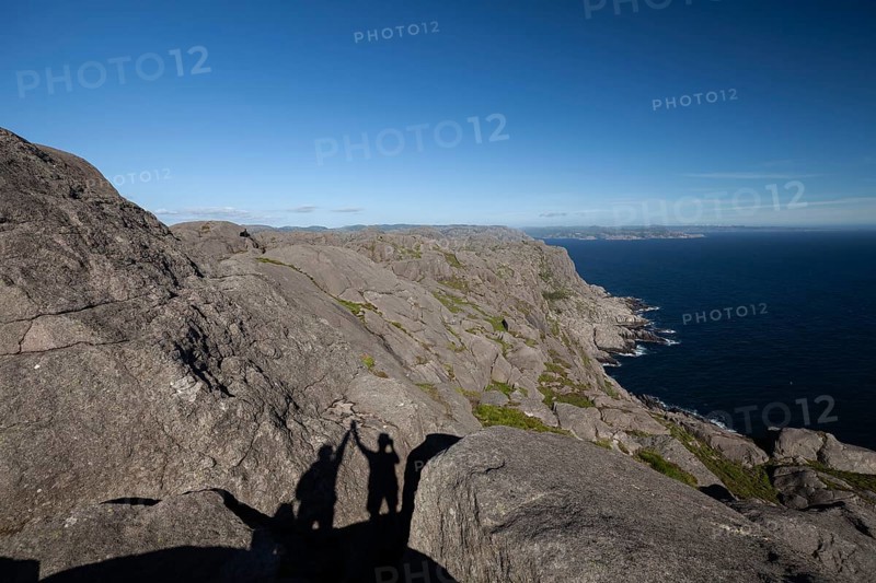 Shadow of two people giving a high five on a hiking trail view. Summer, Sandvika (Sandviga), Agder, Norway