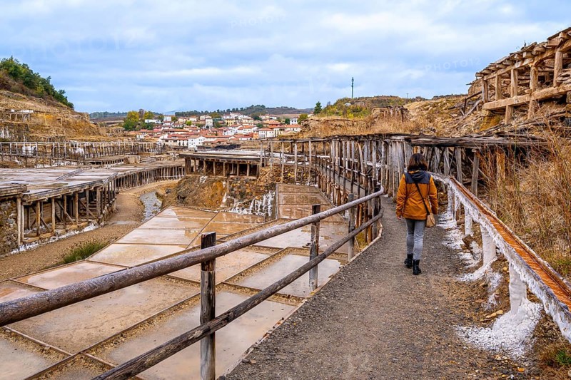 Woman walking along a path next to the historic terraced salt evaporation ponds of the salt valley, an old, traditional industry in the basque country