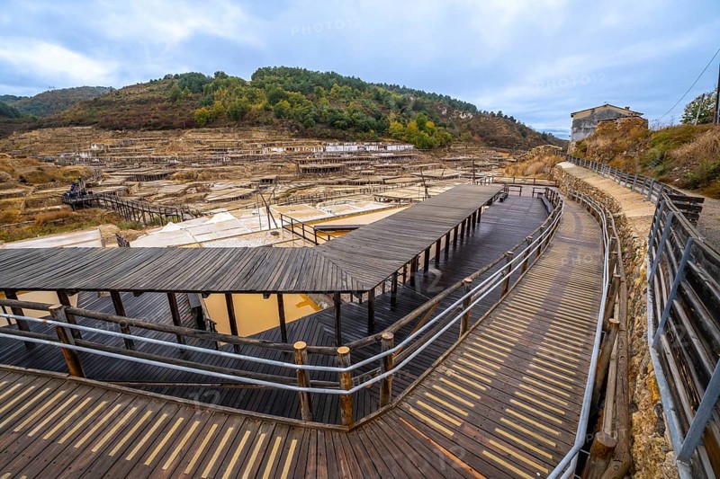 Salt evaporation ponds filling the salt valley of anana, showing traditional brine extraction methods and historic architecture with wooden walkways for visitors