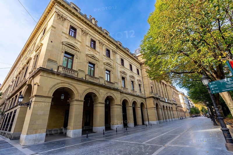 Gipuzkoa square facade in san sebastian with repeating stone arches and windows along a tree lined street, classic ornate architecture framing a peaceful urban scene