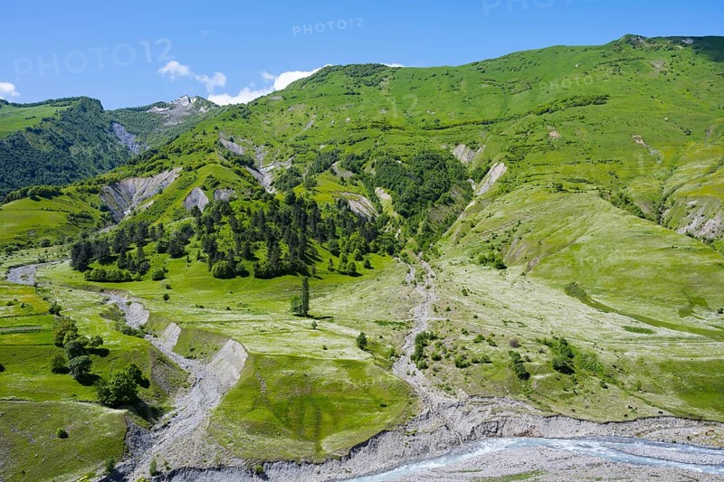 Green hills with a valley and river, surrounded by mountains and lush vegetation, landscape between Kvesheti and Gudauri, White Aragvi River, Mtskheta-Mtianeti region, Georgian Military Highway, High Caucasus, Georgia