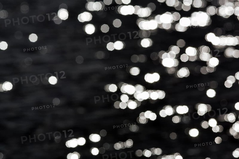 Abstract black background, sparkling white lights, bokeh balls, light reflections on water surface, octagonal light spots, copy space, background image, Sicily, southern Italy, Italy