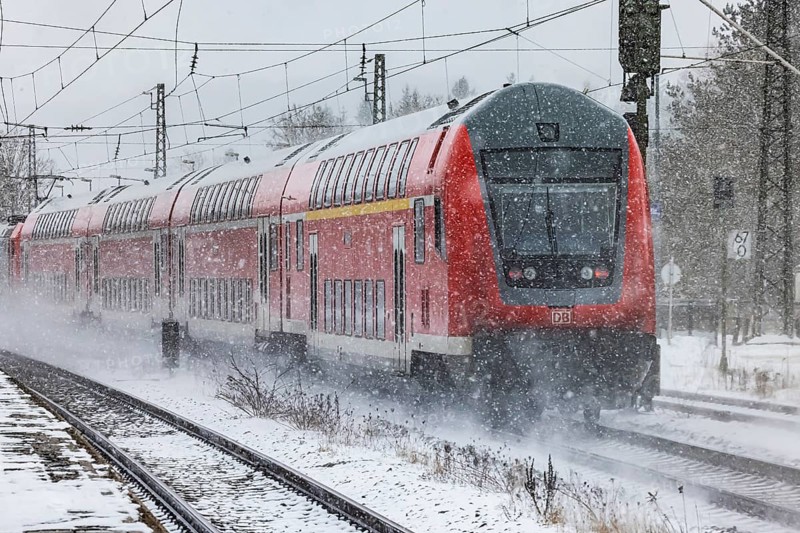 RegionalExpress RE on the road through a winter landscape in snowfall. A train on the line in the Deutsche Bahn AG rail network. Amstetten, Baden-Württemberg, Germany