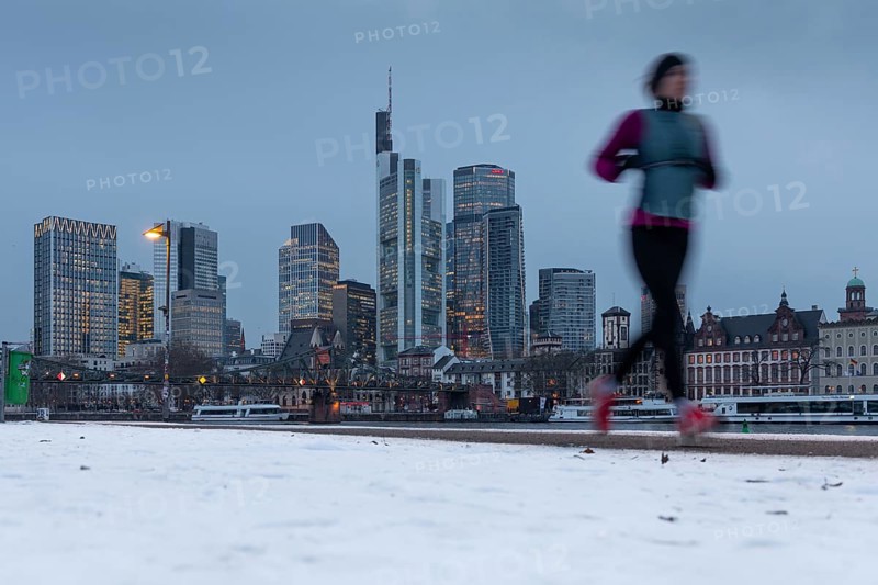 The towers of the Frankfurt banking skyline rise behind the snow-covered banks of the Main, Frankfurt am Main, Hesse, Germany
