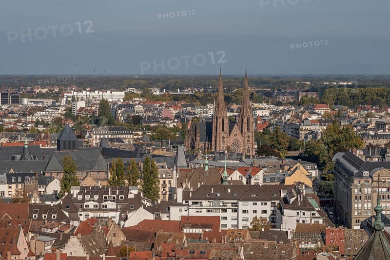 The stone balcony offers a view of the city of Strasbourg. Houses and buildings can be seen under a cloudy sky. Architectural details surround the balcony. Bas Rhin, Alsace, France