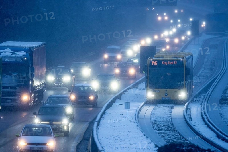 Winter weather, motorway traffic, A40 motorway, Ruhrschnellweg, in Essen, at the Essen-East motorway junction, snowfall, traffic jams, heavy flowing traffic, bus lane between roads, public transport, North Rhine-Westphalia, Germany
