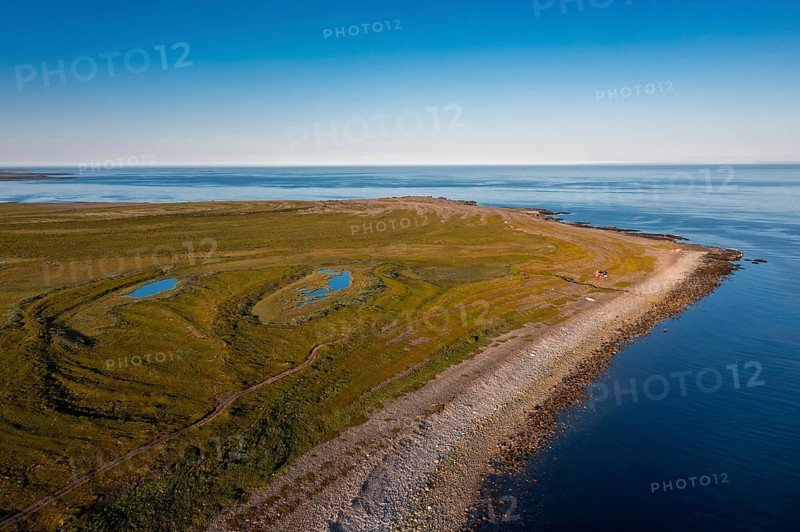 Coastal landscape on Varangerfjord with blue sky, still sea, moors and pebble beach aerial view, Barents Sea, Finnmark, Norway