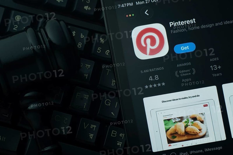 Dhaka, Bangladesh- 28 Oct 2025: An iPad displaying the Pinterest app against a judge's gavel and dark keyboard background