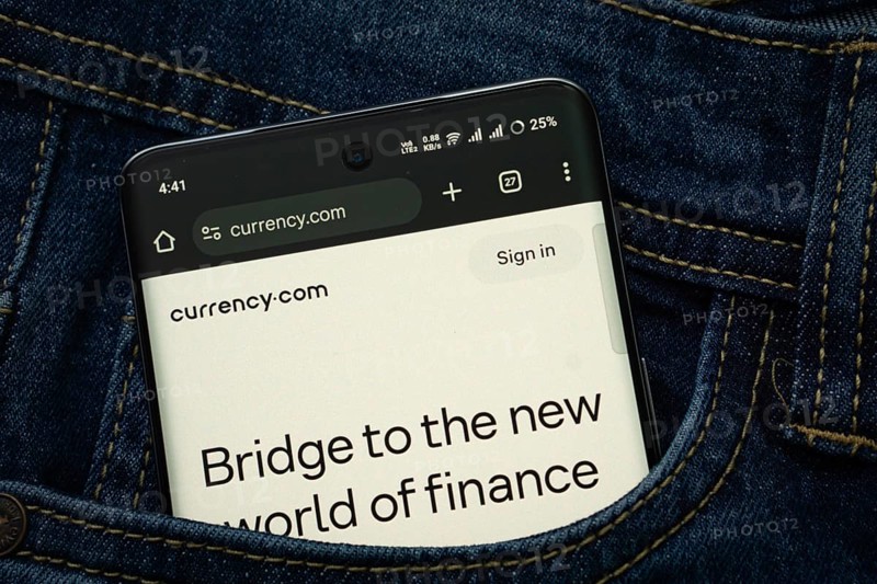Dhaka, Bangladesh- 15 June 2025: A smartphone displaying the Currency.com web interface peeks out of a denim pocket