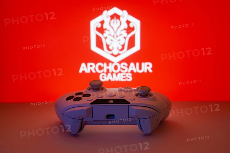 Dhaka, Bangladesh- 08 Apr 2025: A gaming controller in front of a Archosaur Games screen