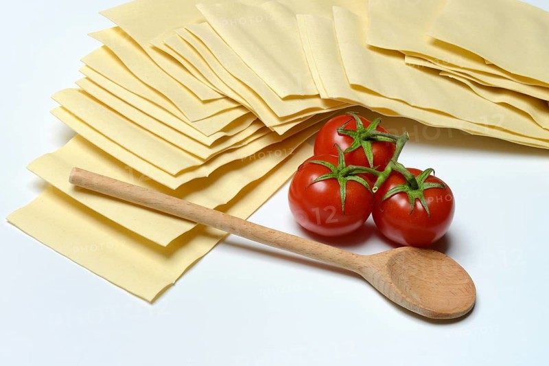 Lasagna, dried lasagna leaves with tomatoes and cooking spoon
