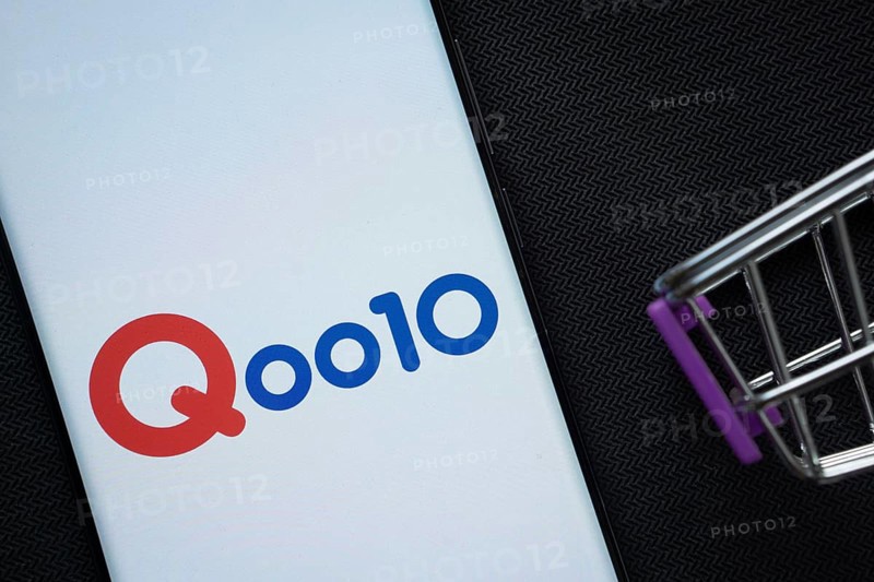 Dhaka, Bangladesh- 03 July 2025: A smartphone displaying the Qoo10 logo next to a miniature shopping cart on a background