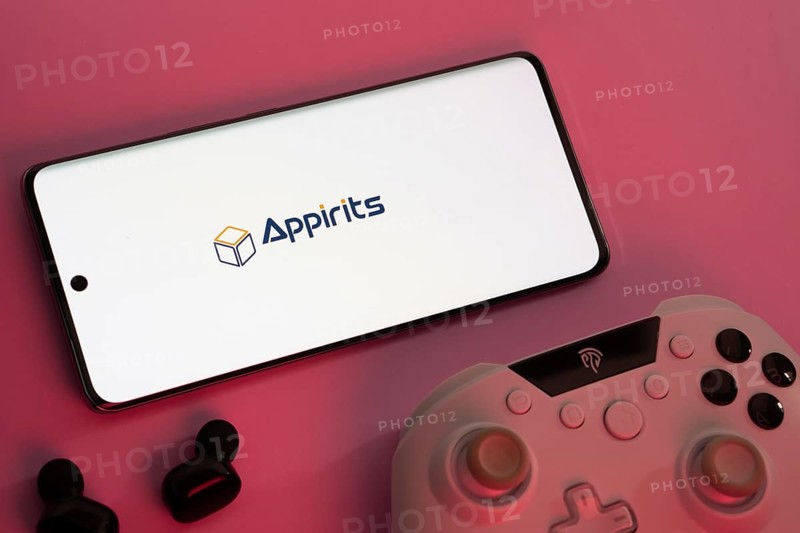Dhaka, Bangladesh- 08 Apr 2025: A smartphone displaying the Appirits logo next to a gaming controller and earbuds on a pink surface