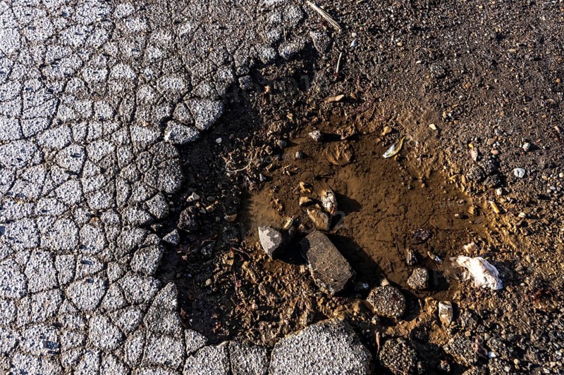 Pothole, asphalt surface, floor, with many small cracks, roadway, parking lot