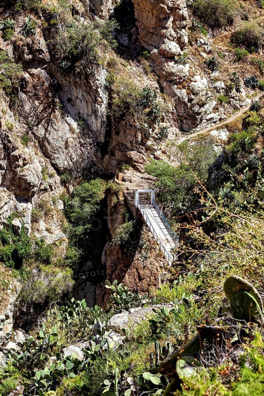 Suspension bridge that crosses a deep gorge between rocks, The landscape of the Colca Canyon in the Andes of Peru
