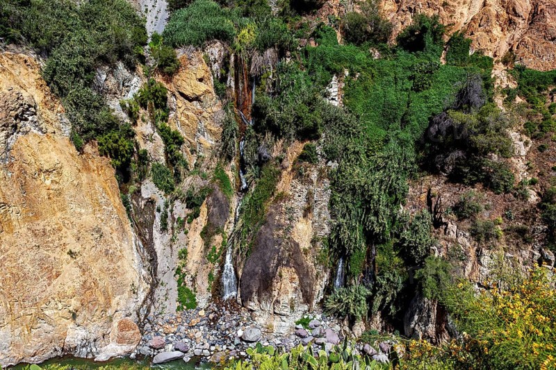 Small waterfall flowing over green and rocky cliffs, the landscape of the Colca Canyon in the Andes of Peru