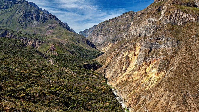Narrow river snakes through a deep gorge between green mountains, the landscape of Colca Canyon in the Aden of Peru