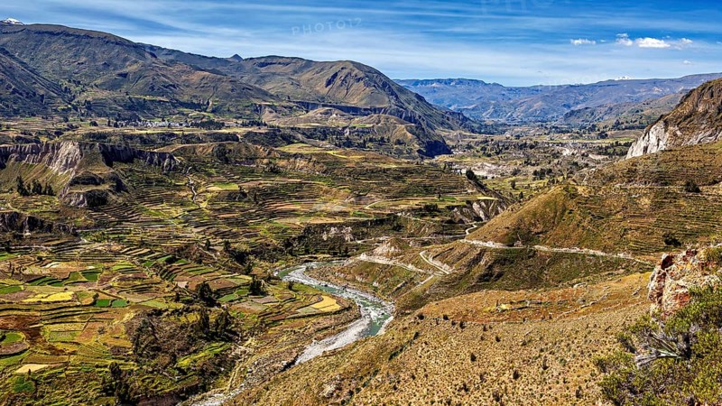 Extensive terraced valleys with towering mountains and a river, the landscape of the Colca Canyon in the Aden of Peru
