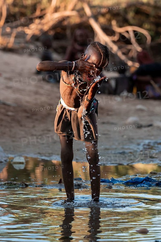 Himba child washing with water on a river, traditional Himba, Kaokoveld, Kunene, Namibia