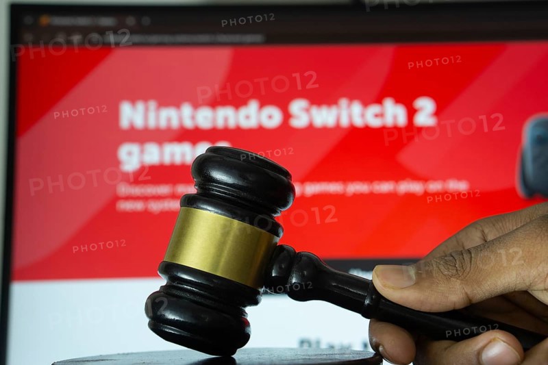 Dhaka, Bangladesh- 20 June 2025: A hand holds a gavel in front of a computer screen displaying Nintendo's website