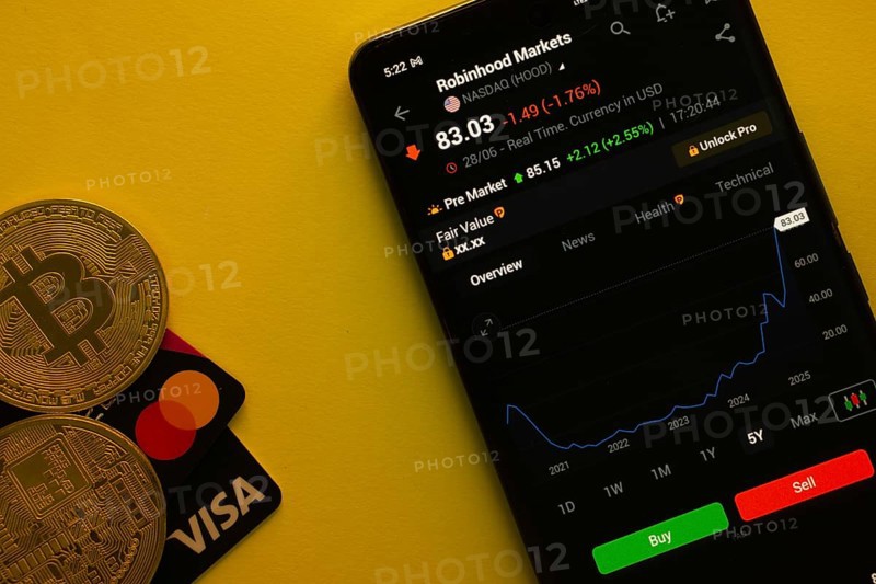 Dhaka, Bangladesh- 30 June 2025: Smartphone displaying Robinhood Markets stock data on a trading app with Bitcoin, Visa and Mastercard card on a vibrant yellow background