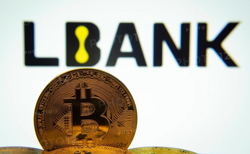 Dhaka, Bangladesh- 03 Sep 2025: Close-up of Bitcoin coins with the LBank logo visible on a screen in the background