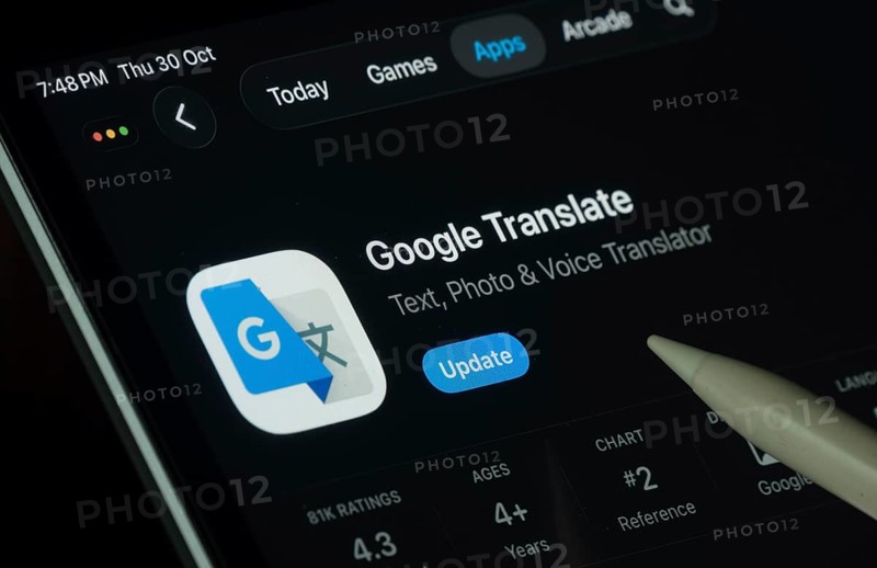 Dhaka, Bangladesh- 30 Oct 2025: Google Translate app displayed on a iPad screen in dark mode with a digital pen pointing at it