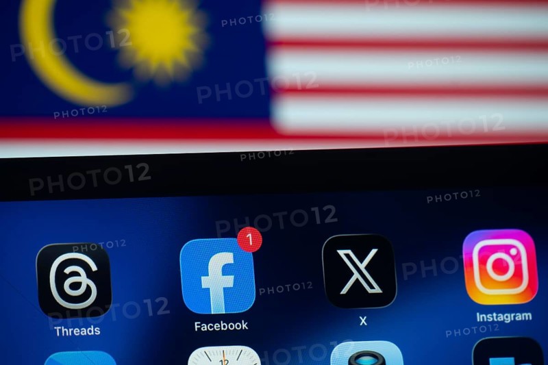 Dhaka, Bangladesh- 01 Dec 2025: Facebook, X, Threads, Instagram apps are displayed on a smartphone screen, and the Malaysian flag is visible in the background
