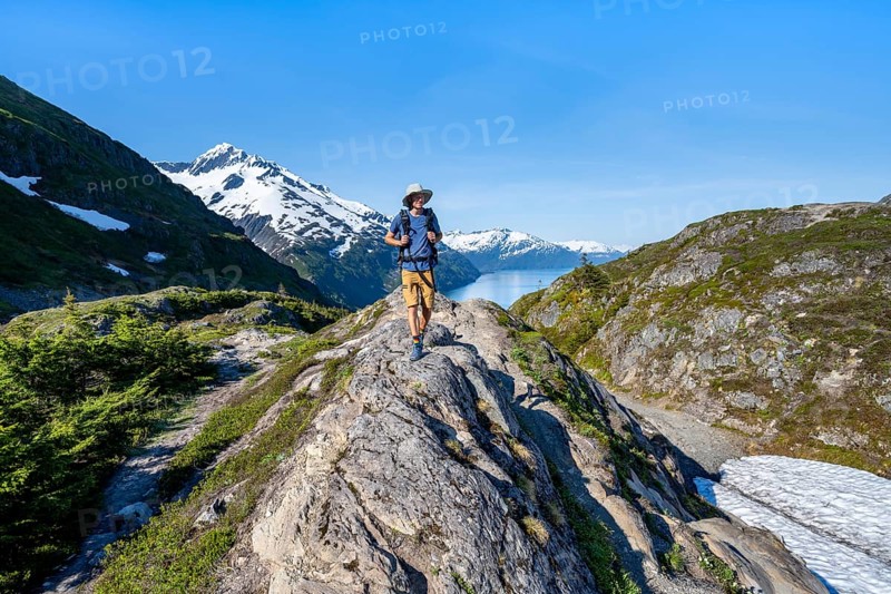 Hikers on Portage Pass, snow-covered mountains and Fjord Passage Canal, near Whittier, Alaska, USA