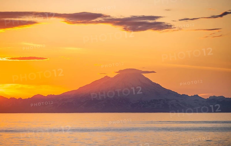 View of Cook Inlet on white mountain peaks of Mount Redoubt at sunset, picturesque golden light of the midnight sun, mountains of the Aleutian Range, Anchor Point, Anchor River State Recreation Area, Alaska, USA