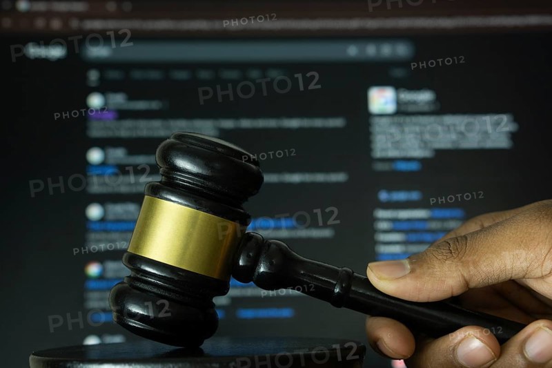 Dhaka, Bangladesh- 20 June 2025: A hand holds a gavel in front of a computer screen displaying Google's website