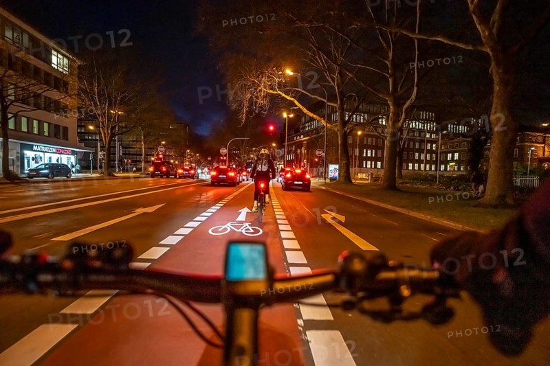 Cycling in the city, in the dark, in the evening, cycling on a bike lane, marked in red, Huyssenallee, in downtown Essen, North Rhine-Westphalia, Germany
