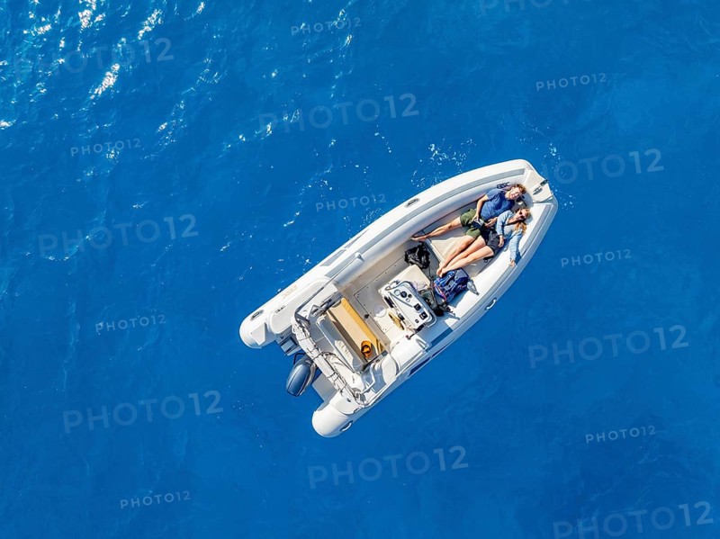 Young woman and young man lying in a motor boat on a blue sea, top-down, aerial view, Golfo di Orosei, Baunei, Sardinia, Italy