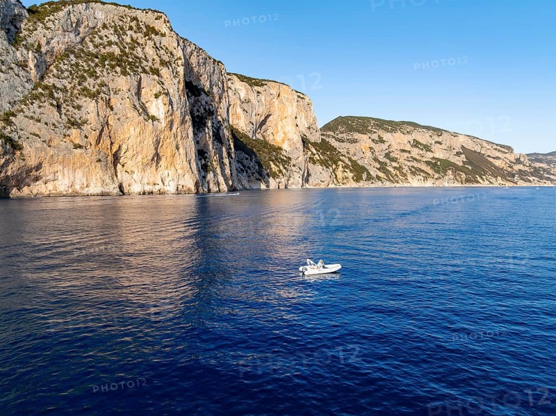 Motorboat off picturesque rocky coast ImmorgenLicht, cliffs, Golfo di Orosei, Baunei, Sardinia, Italy