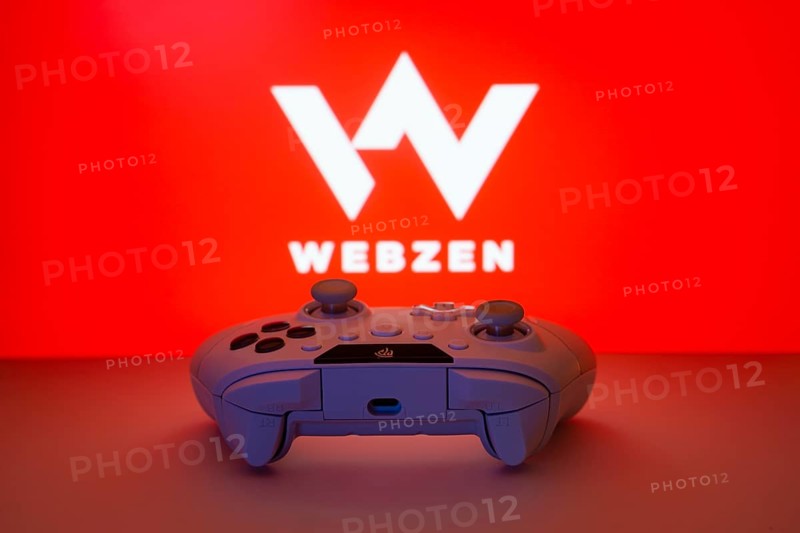 Dhaka, Bangladesh- 14 Nov 2025: A close-up of a white gamepad with the Webzen seen on screen in the background