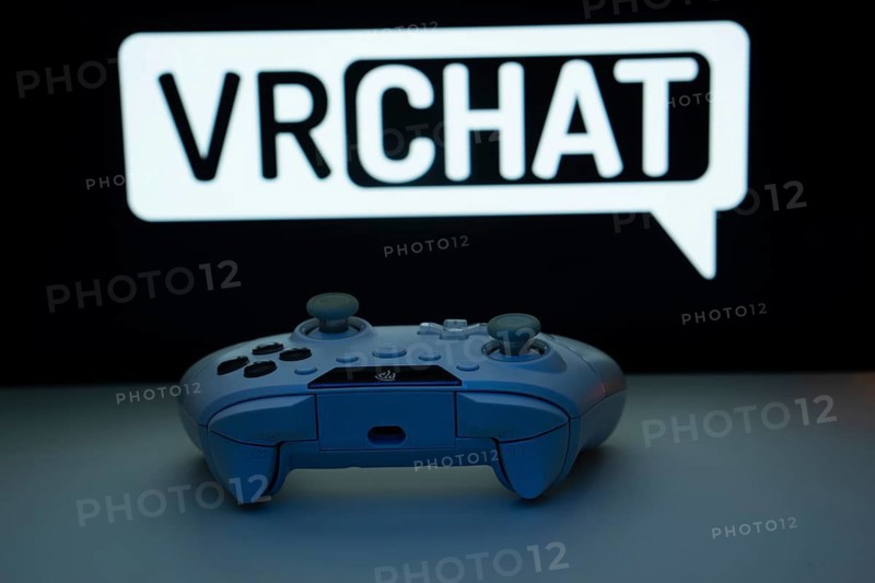 Dhaka, Bangladesh- 14 Nov 2025: A close-up of a white gamepad with the VRChat seen on screen in the background