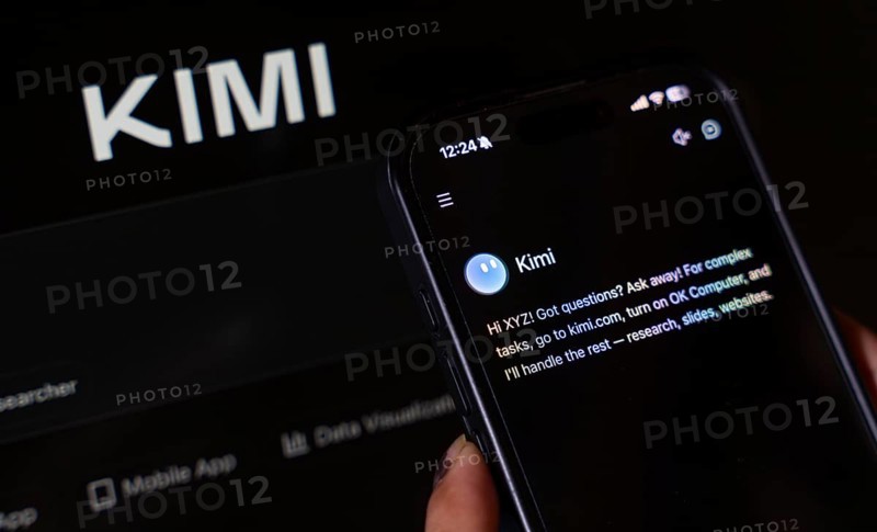 In this photo illustration, a person uses the Kimi AI chatbot on a smartphone while the KIMI logo is displayed on a screen in the background, in New Delhi, India on 20 November 2025. Kimi AI is a Chinese artificial intelligence chatbot and assistant developed by Moonshot AI, a fast-growing tech company in China