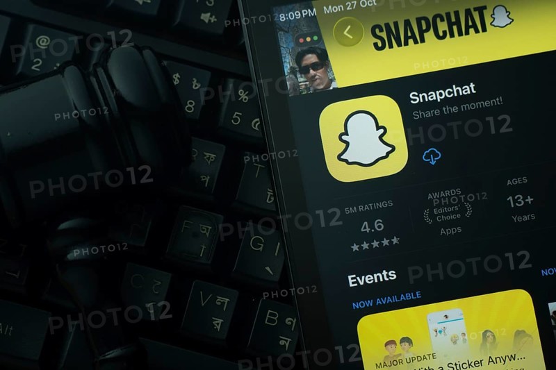 Dhaka, Bangladesh- 28 Oct 2025: An iPad displaying the Snapchat app against a judge's gavel and dark keyboard background