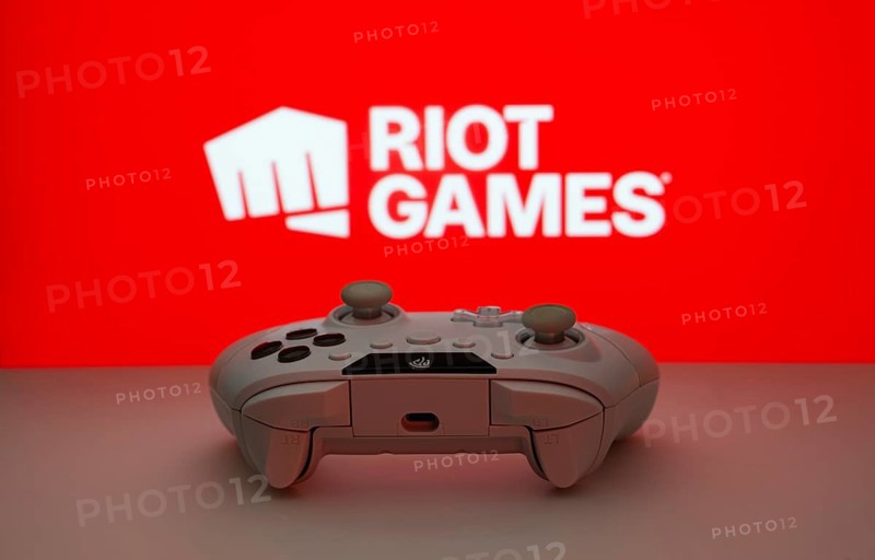 Dhaka, Bangladesh- 14 Nov 2025: A close-up of a white gamepad with the Riot Games seen on screen in the background