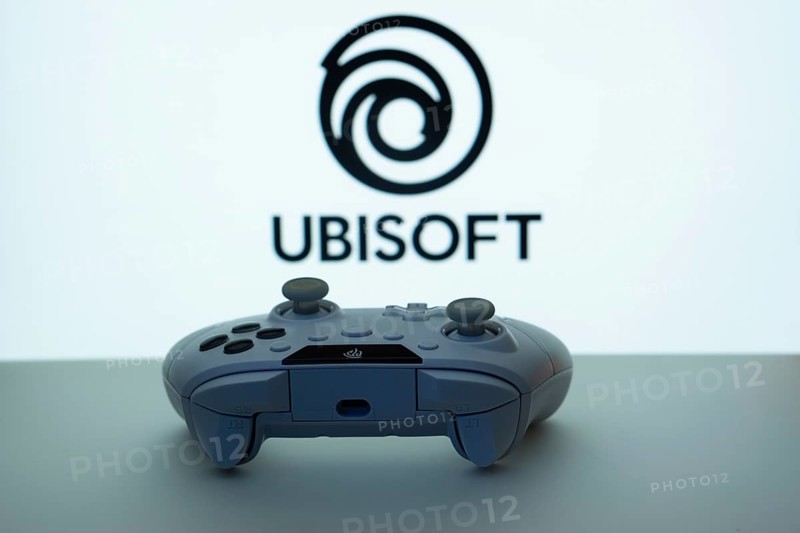 Dhaka, Bangladesh- 14 Nov 2025: A close-up of a white gamepad with the Ubisoft seen on screen in the background