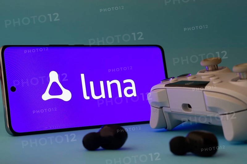 Dhaka, Bangladesh- 23 Mar 2025: A smartphone with a Amazon Luna icon next to a controller and earbuds on a blue surface