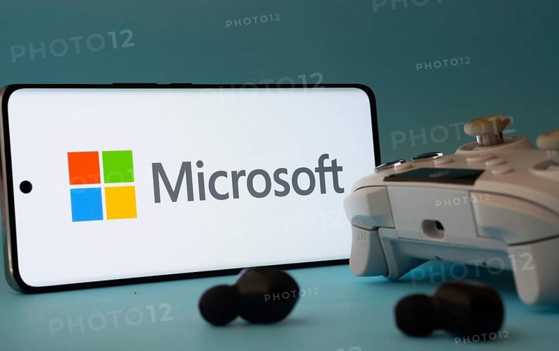 Dhaka, Bangladesh- 23 Mar 2025: A smartphone with a Microsoft icon next to a controller and earbuds on a blue surface