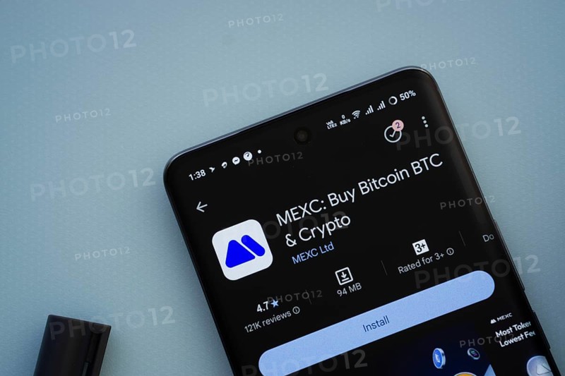Dhaka, Bangladesh- 29 May 2025: On a blue surface, a smartphone displays the MEXC app within the Google Play Store