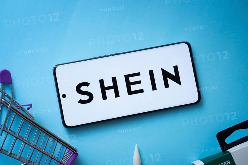 Dhaka, Bangladesh- 03 July 2025: Smartphone displaying SHEIN logo with shopping cart on a blue background