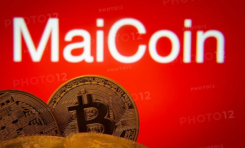 Dhaka, Bangladesh- 03 Sep 2025: Close-up of Bitcoin coins with the MaiCoin logo visible on a screen in the background