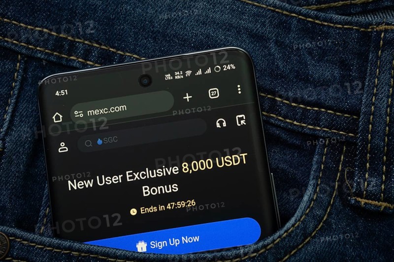 Dhaka, Bangladesh- 15 June 2025: A smartphone displaying the MEXC web interface peeks out of a denim pocket