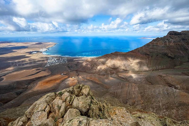 View from the Risco de Famara cliffs to the coast and the sea with the Famara beach, Playa de Famara, Lanzarote, Canary Islands, Spain