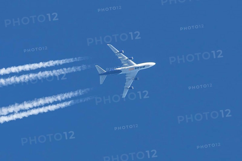 Boeing 747 jumbo jet cargo aircraft of Atlas air airlines flying in a blue sky with contrails or vapour trails behind, England, United Kingdom